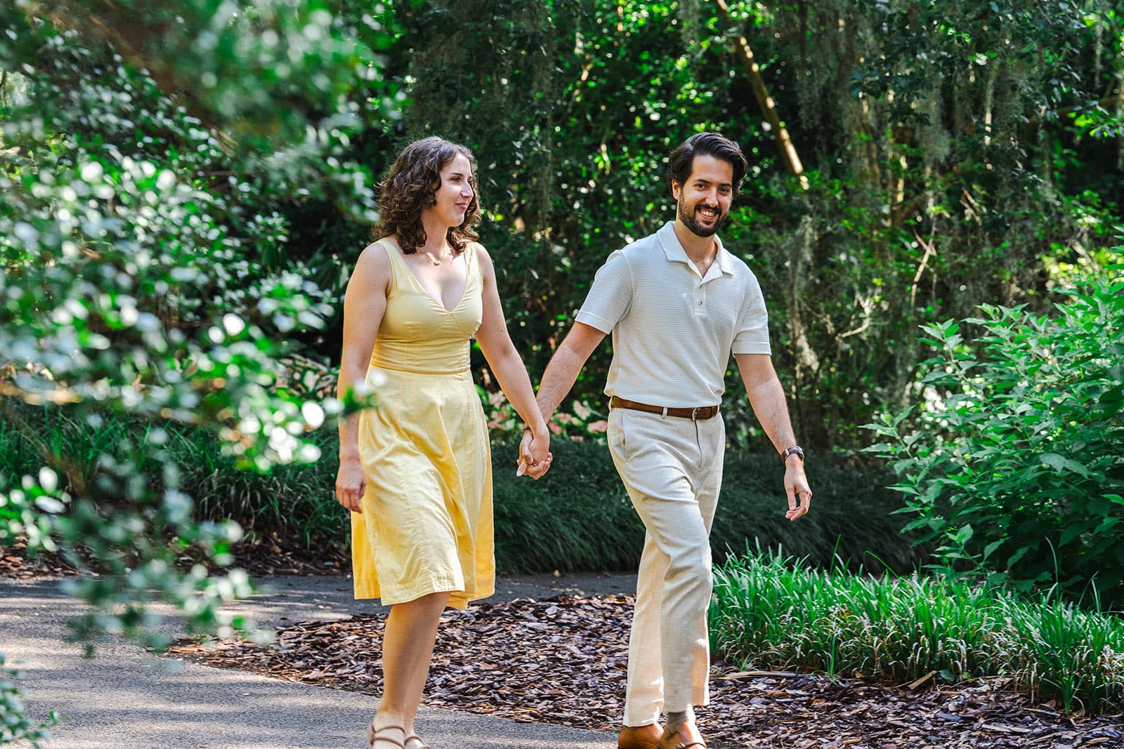 Couple walking hand in hand through gardens